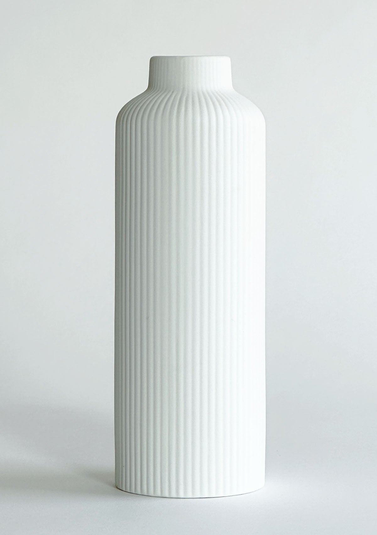 Schmale, hohe Keramikvase in mattem Weiß – minimalistisches, elegantes Design, ideal um einzelne Trockenblumen oder Blumensträuße stilvoll zu präsentieren.