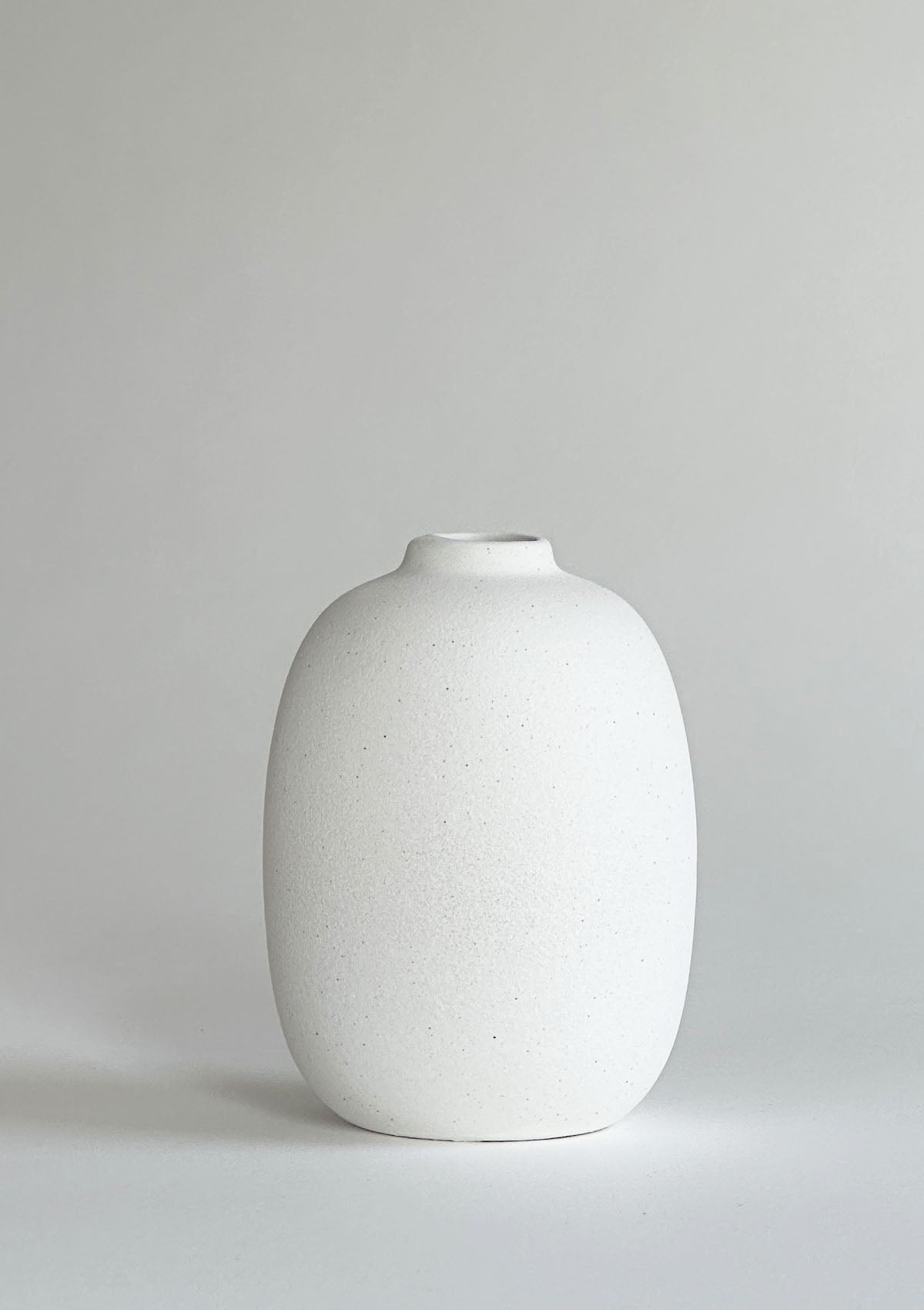 Kleine ovale Keramikvase in Weiß – einzigartiges, platzsparendes Design, perfekt für einen kurzen Trockenblumen-Zweig oder ein paar Blüten auf dem Tisch.