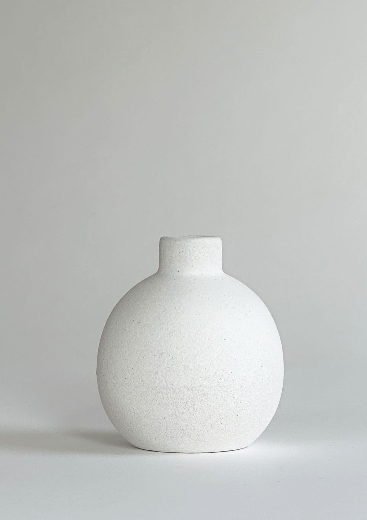 Kleine runde Keramikvase in Weiß – schlichtes, kugelförmiges Design, perfekt um eine einzelne Blume oder ein paar Trockenblumen stilvoll zu präsentieren.